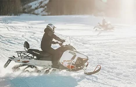 A snowmobile rider on a snowy trail