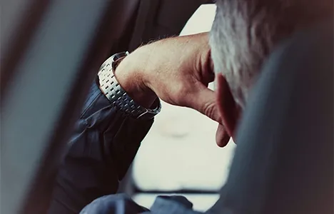 A person wearing a wristwatch seated in a car